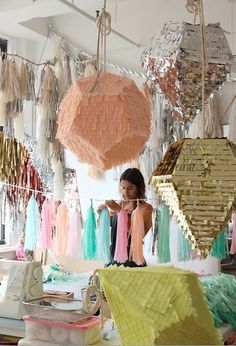 a woman standing in front of a table filled with lots of different colored paper decorations