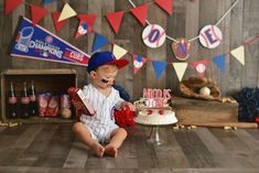 a young boy sitting on the floor in front of a cake with baseball themed decorations