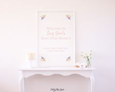 a baby shower sign sitting on top of a table next to a vase with flowers