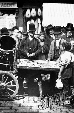 an old black and white photo of people standing around a table