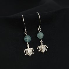 Display your love of sea turtles with our dainty sea turtle earrings! You'll love the simple design and detailed turtle charms. A perfect gift for turtle and ocean lovers! Materials: sterling silver wire and turtle charm (1x1cm, one-sided) Beads: mint green quartzite Sizing Details: (earring box is 2x3 inches for size reference) Total Length: 1.5 in. (3.75cm) Width: .25 in. (.5cm) Handmade Sterling Silver Turtle Jewelry, Handmade Turtle-shaped Sterling Silver Jewelry, Green Quartzite, Clean Sterling Silver, Silver Sea, Earring Box, Turtle Charm, Turtle Earrings, Sea Turtles