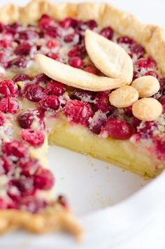 a pie with cranberry and almond toppings on a white plate, ready to be eaten