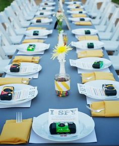 a long table set up with white chairs and yellow napkins