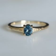 a gold ring with a blue topazte in the center on a white surface