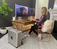 a woman sitting at a desk in front of a computer monitor with a keyboard and mouse