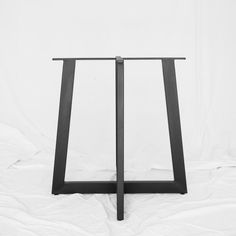 a black and white photo of a table with two legs that are bent to the side