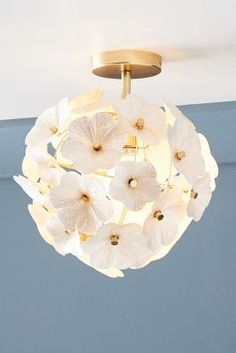 a light fixture with white flowers hanging from the ceiling