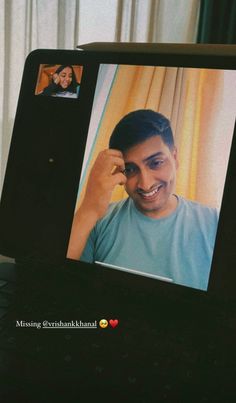 a man is smiling and talking on his cell phone while sitting in front of a laptop