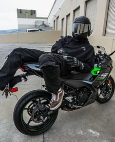 a man sitting on top of a motorcycle in front of a garage door with his feet up