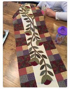 a woman sitting at a table working on a quilt