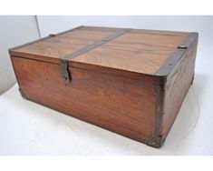 an old wooden box sitting on top of a white table next to a wall or floor