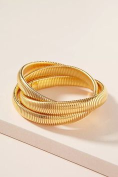 Unveil a touch of exotic opulence with the Golden Cobra Triple-Stack Bangle. Crafted meticulously from gold-plated brass, this chunky slip-on piece merges three thick, intertwined bands, reminiscent of the majestic coils of a cobra. Its layered, entwined design encapsulates the strength and allure of its namesake, making it a standout piece in any jewelry collection. Whether you're stepping out for a casual event or elevating a sophisticated ensemble, this bangle promises to be the centerpiece o Gold Flexible Slinky Bracelet, Adjustable Gold Slinky Bracelets, Gold Slinky Metal Jewelry, Corporate Chic, Sleek Ponytail, Stacked Bangles, Form Fitting Dress, Coils, Pet Hair