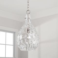 a clear glass light fixture hanging from a ceiling in a room with white walls and windows