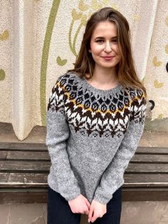 a woman standing in front of a curtain wearing a sweater with an argyle pattern on it