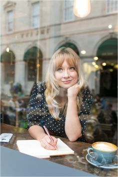 a woman sitting at a table in front of a window with a pen and paper