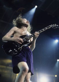 a man standing on top of a stage holding a guitar