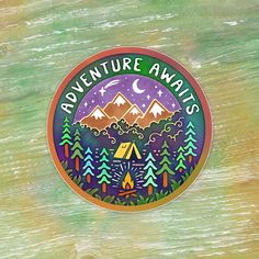 the adventure awaits sticker is shown on a wooden surface with trees and mountains in the background