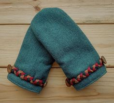 two green mittens sitting on top of a wooden table