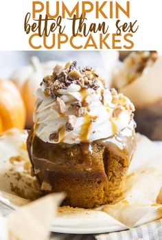 a close up of a cupcake on a plate with whipped cream and pumpkins in the background