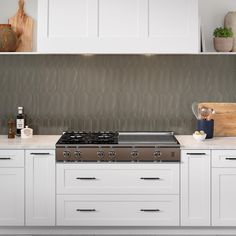 a stove top oven sitting inside of a kitchen next to white cupboards and counter tops