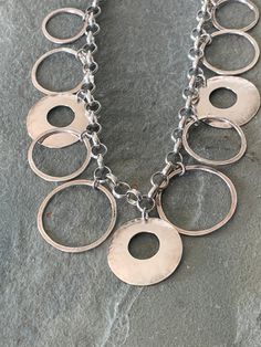 "Sterling silver circle necklace made in Israel - this is a really fun piece!  The base is a 17\" rolo chain that has 6mm round links and dangling from those links is a variety of circles, different sizes and some thicker ones that are hammered.  The measurements are as indicated and the total weight is 33.96 grams.  It can be adjustable if the clasp is attached to any one of the loops in the chain but obviously, cannot be bigger than 17\"." Silver Circle, Circle Necklace, Rolo Chain, Chains Necklace, Washer Necklace, Circles, Chain Necklace, Jewelry Necklaces, Sterling Silver