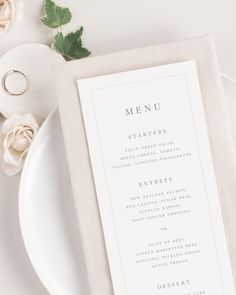 a menu card sitting on top of a white plate next to a rose and napkin