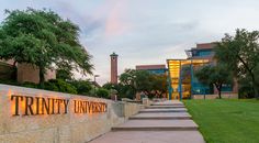 there is a sign that says trinity university on the side of a wall in front of a building