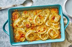 a blue casserole dish filled with onion rings on a wooden table, ready to be eaten