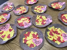 paper plates with cut out hearts and sticky notes on them sitting on a wooden table