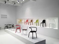 several different colored chairs on display in a white room