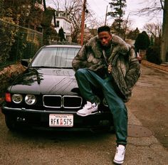 a man sitting on the hood of a black car