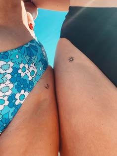 two women in swimsuits standing next to each other with tattoos on their butts