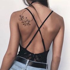 the back of a woman's top with flowers tattooed on her upper and lower back