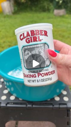 a woman holding up a cup of baking powder in front of a blue bowl with white polka dots