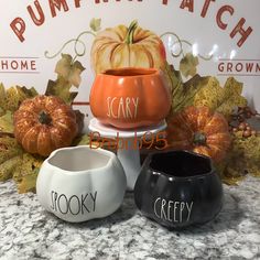 three ceramic pumpkins sitting on top of each other in front of a fall sign