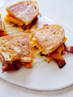 two grilled sandwiches on a white plate with bacon and melted cheese in the middle