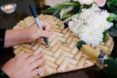 two hands writing on a piece of bread with flowers and candles in the back ground