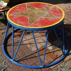 a red and yellow table sitting on top of a brick floor next to a chair