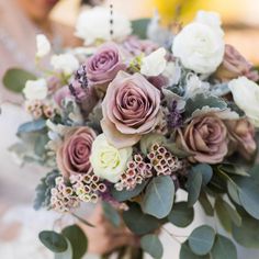 a bride holding a bouquet of flowers and greenery