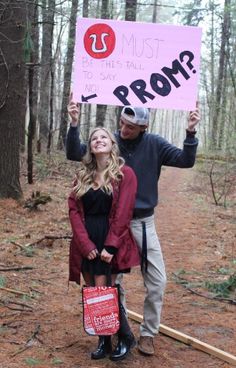 a man and woman standing in the woods holding up a sign that says, what must i prom?