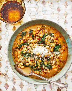 a bowl of soup with spinach, chickpeas and parmesan cheese