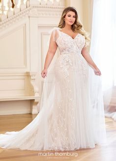 a woman in a wedding dress standing on a wooden floor next to a stair case