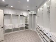 an empty walk - in closet with white cabinets and drawers