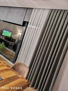 a room with a wooden table and chairs in front of a sliding glass door that has a television on it