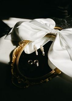 a pair of earrings sitting on top of a white cloth next to a black box