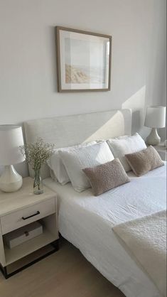 a bed with white sheets and pillows in a room