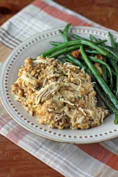 a white plate topped with green beans and meat covered in gravy on top of a wooden table