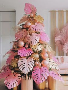 a pink and gold christmas tree in a living room with monster leaves on the top