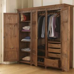 an open wooden wardrobe with clothes hanging on it