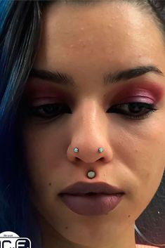 a woman with blue hair and piercings on her nose